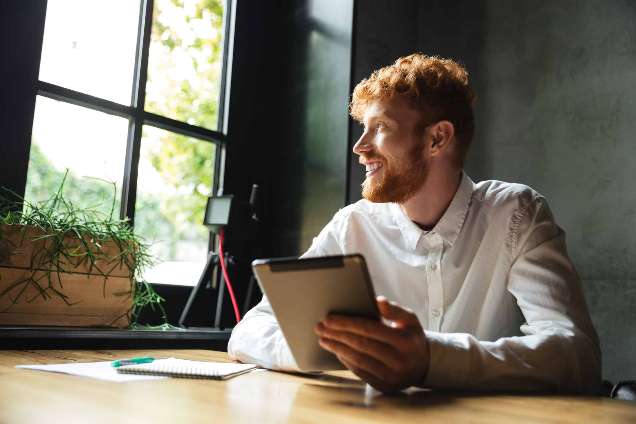 photo young handsome readhead bearded man holding tablet looking big window scaled
